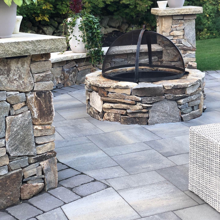 Application image for Granite - Nutmeg Ridge. The image shows this material being used for outdoor fire concepts, full bed veneer and thin veneer. The dominant color shown is gray. The color mix creates a warm feeling.