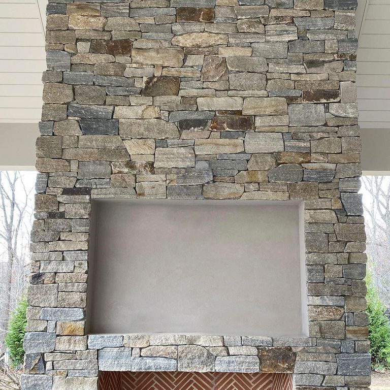 Application image for Montauk Blend Granite. The image shows this material being used for fireplace surround and thin veneer. The surface finish shown is . The dominant color shown is gray. The color mix creates a warm feeling. Regular and linear color patterns.