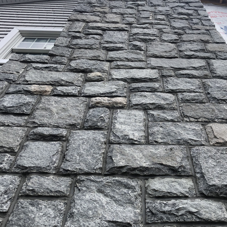Application image for Greenwich Blue Granite. The image shows this material being used for full bed veneer and thin veneer. The surface finish shown is pillowed. The dominant color shown is gray. The color mix creates a cool feeling. Regular color pattern.