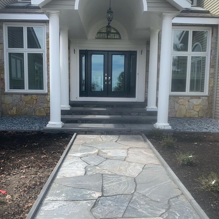 Feature image for American Mist Granite. The image shows this material being used in a path pavers application. The dominant color shown is gray; with beige and white secondaries. Exhibits 