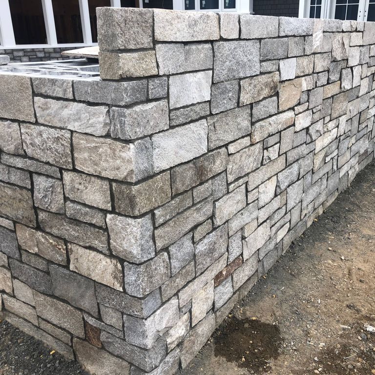 Application image for Harbor Mist Granite. The image shows this material being used for full bed veneer and thin veneer. The surface finish shown is split-face. The dominant color shown is gray. The color mix creates a warm feeling. Regular color pattern.