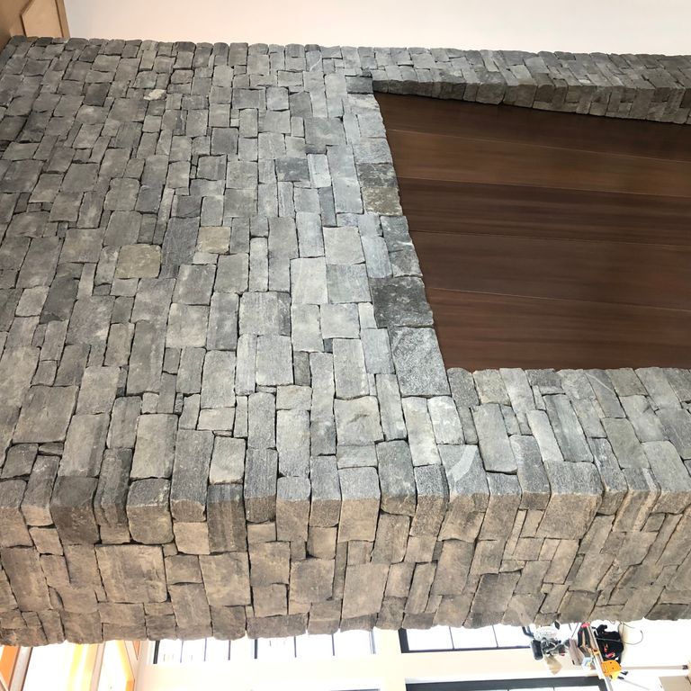 Application image for Granite - Spruce Mountain. The image shows this material being used in a fireplace mantel application. The dominant color shown is gray. The color mix creates a warm feeling. Fine speckled and random color patterns.