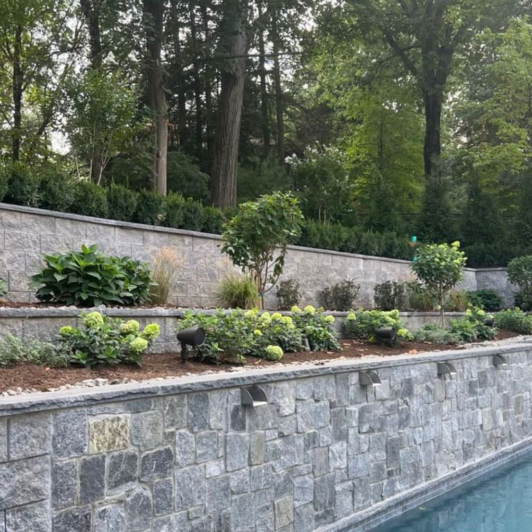 Application image for Granite - Spruce Mountain. The image shows this material being used in a retaining wall application. The dominant color shown is gray. The color mix creates a warm feeling. Speckled and random color patterns.