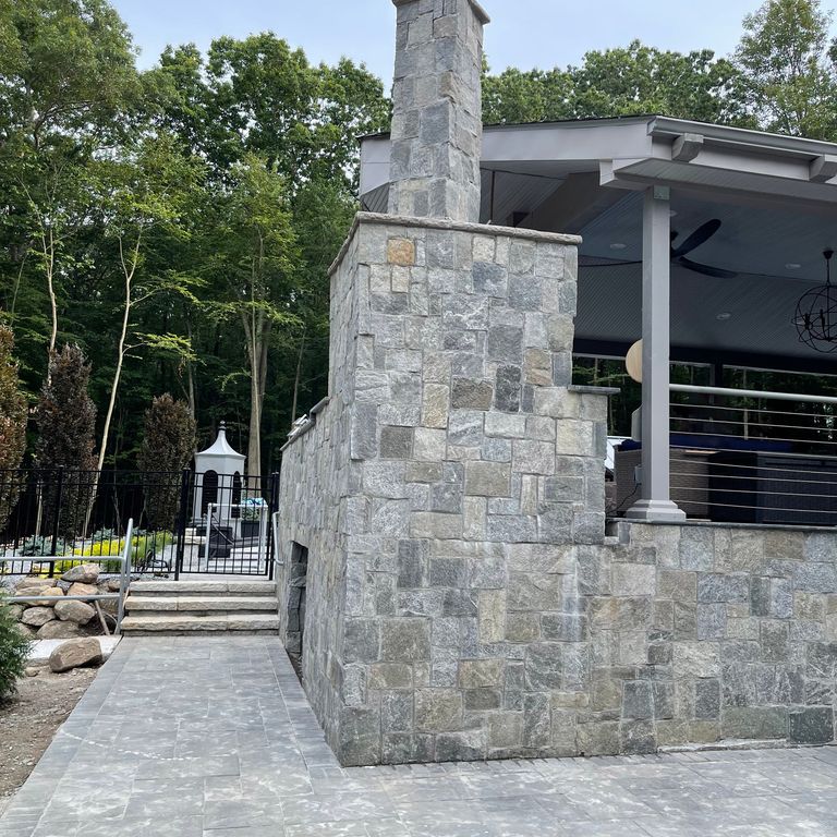 Application image for Granite - Spruce Mountain. The image shows this material being used in an outdoor fire concepts application. The dominant color shown is gray. The color mix creates a warm feeling. Speckled and random color patterns.