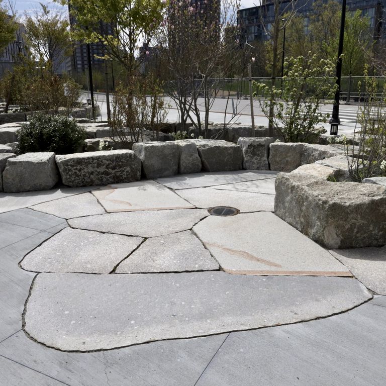 Application image for Granite - New England Mix. The image shows this material being used for patio pavers and public area. The dominant color shown is gray.