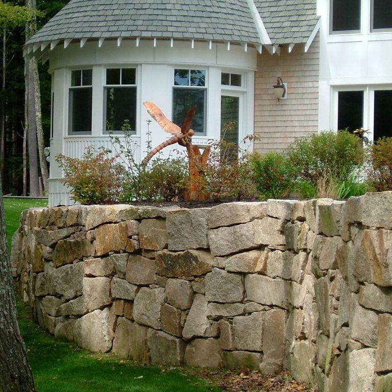 Application image for Millenium Granite. The image shows this material being used in a landscape wallstone application. The surface finish shown is split-face. The dominant color shown is brown. The color mix creates a warm feeling. Regular color pattern.