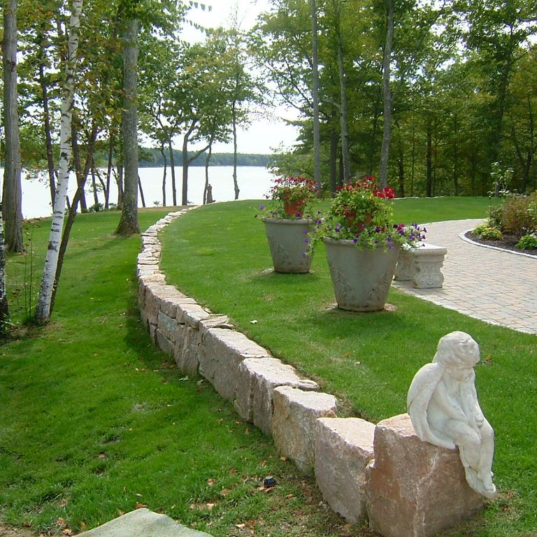 Application image for Millenium Granite. The image shows this material being used in a landscape wallstone application. The surface finish shown is split-face. The dominant color shown is pink. The color mix creates a warm feeling. Solid color pattern.