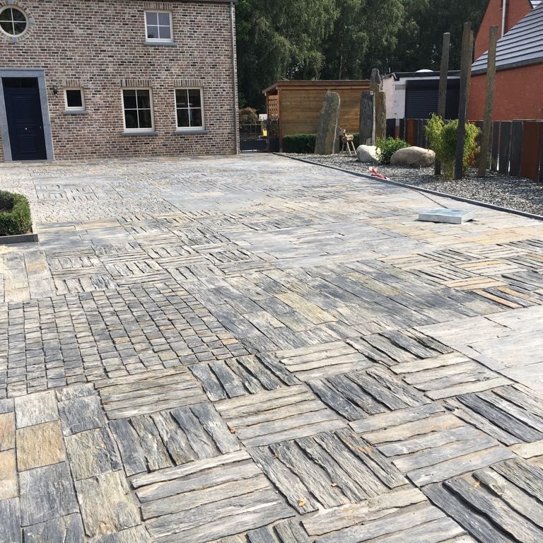 Feature image for Black Shale. The image shows this material being used in a patio pavers application. The dominant color shown is gray; with beige, brown, purple, white, tan and cream secondaries. The color mix creates a warm feeling. Blotched and streaked color patterns.