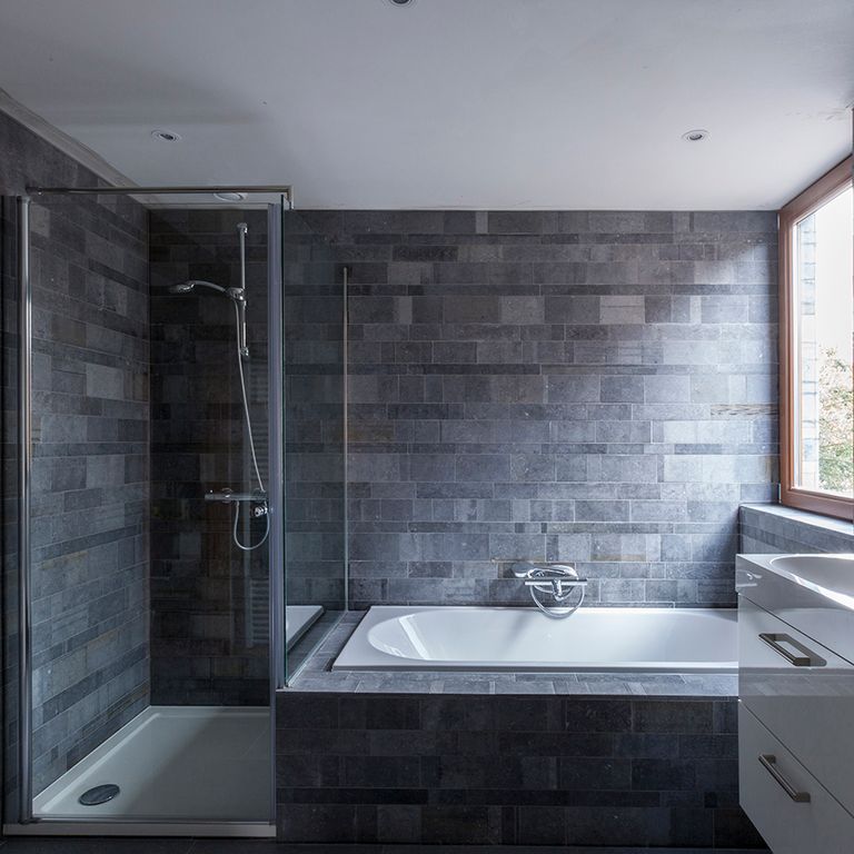 Application image for Limestone - Belgian Bluestone. The image shows this material being used for bath tub & shower and thin veneer. The surface finish shown is acid washed. Dominant colors shown are blue and gray. The color mix creates a cool feeling. Regular color pattern.