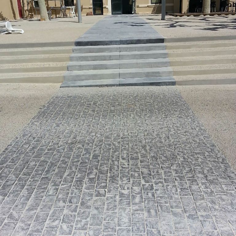 Application image for Limestone - Belgian Bluestone. The image shows this material being used for driveway pavers and monolithic steps. The surface finish shown is a combination of sand blasted and split-face with flat plane. The dominant color shown is gray. The color mix creates a warm feeling. Regular color pattern.