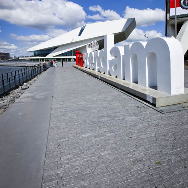 Application image for Limestone - Belgian Bluestone. The image shows this material being used in a patio pavers application. The surface finish shown is a combination of flamed and split-face with flat plane. Dominant colors shown are blue and gray. The color mix creates a cool feeling. Regular color pattern.
