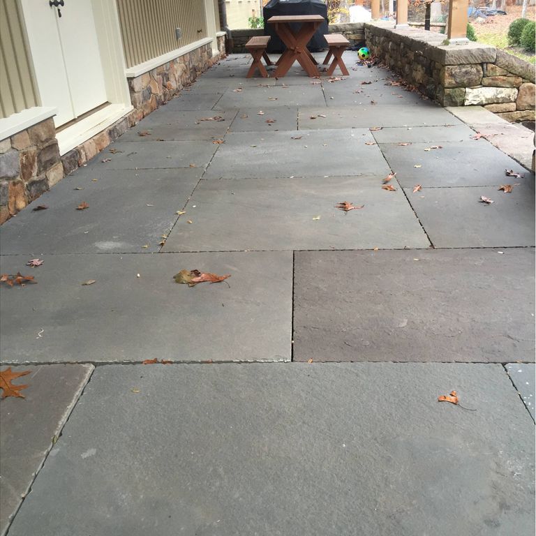 Feature image for Bluestone Natural Cleft - Blue/Gray. The image shows this material being used in a patio pavers application. The dominant color shown is gray. The color mix creates a cool feeling. Solid, regular and cloudy color patterns.