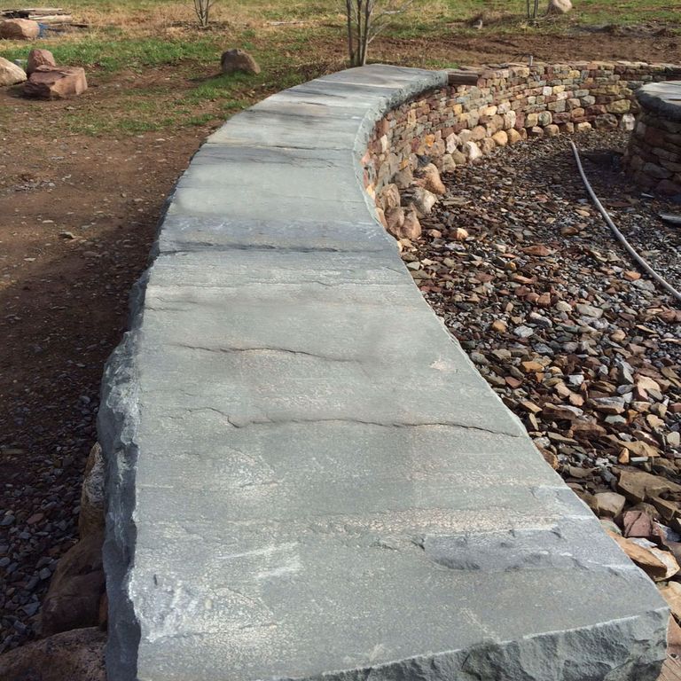 Application image for Bluestone Natural Cleft - Blue/Gray. The image shows this material being used in a wallstone cap application. This is a building and landscape stone for indoor and outdoor commercial and residential applications. Suitable for general use, freeze-thaw conditions, low slipperiness surfaces and high heel compatibilty situations. Low to moderate on the price spectrum.