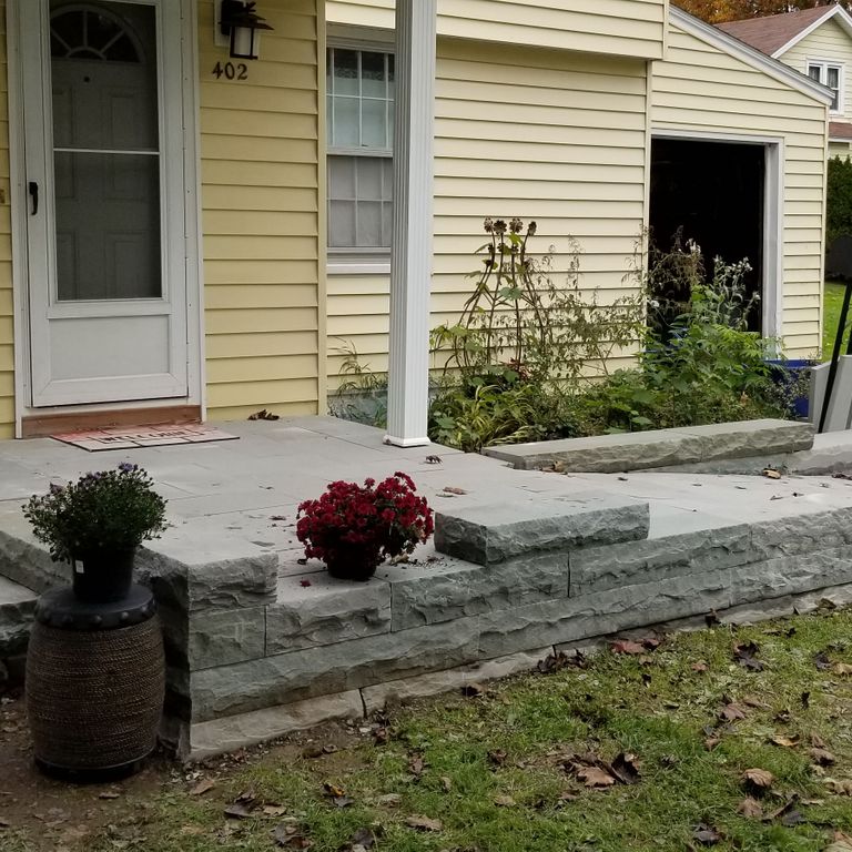 Application image for Bluestone - Blue/Gray - Flamed Finish. The image shows this material being used for landscape wallstone, path pavers, patio pavers and monolithic steps. Dominant colors shown are brown and gray. The color mix creates a warm feeling.