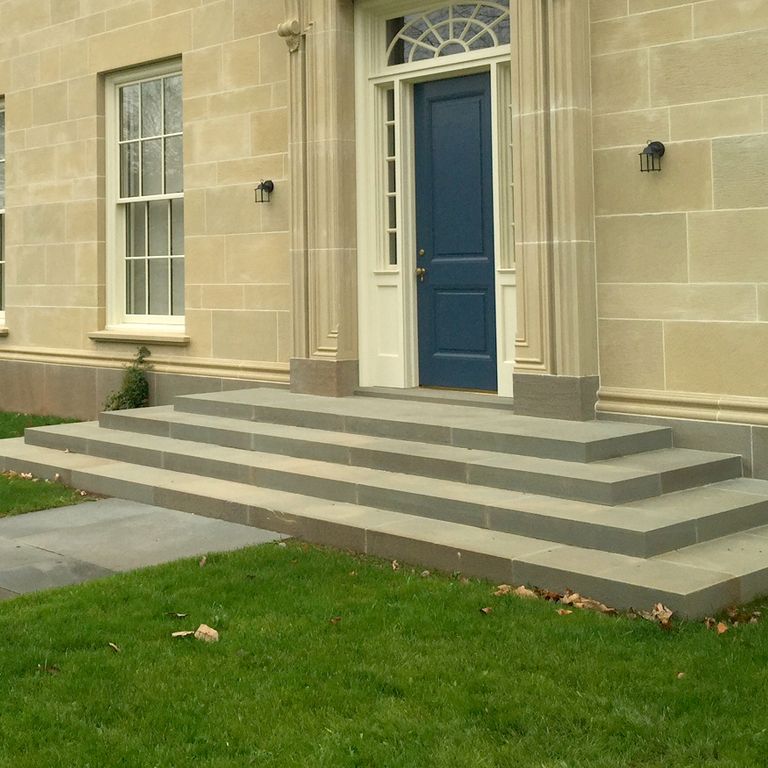 Feature image for Bluestone Flamed Surface - Green/Brown. The image shows this material being used in a path pavers application. Dominant colors shown are beige and gray. Exhibits 