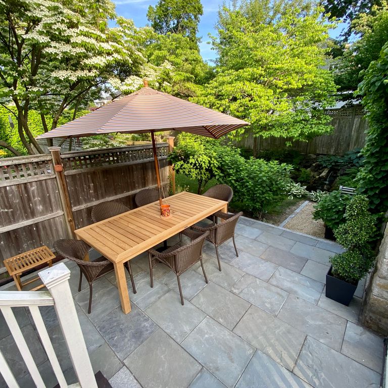 Application image for Bluestone Natural Cleft - Clear Color Mix. The image shows this material being used in a patio pavers application. The surface finish shown is natural cleft. Dominant colors shown are blue, green and gray.