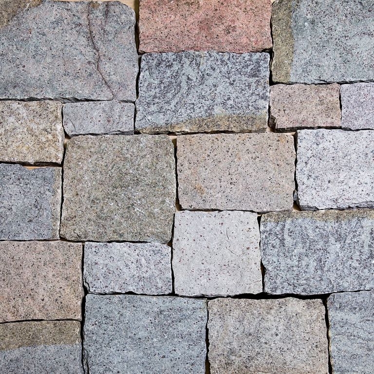 Best close-up image for Adirondack Elite Granite. The image shows this material being used for patio pavers, full bed veneer and thin veneer. The surface finish shown is split-face with flat plane. The dominant color shown is gray; with beige, blue, brown, orange/rust, pink, purple, white and tan secondaries. Exhibits 