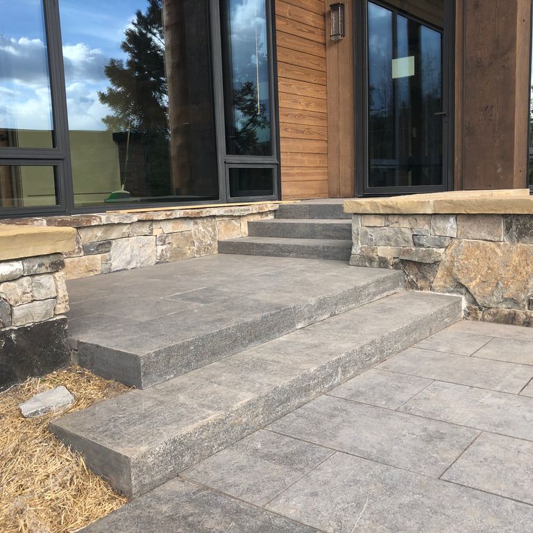 Feature image for Limestone - Highland. The image shows this material being used for path pavers and monolithic steps. The dominant color shown is gray; with beige, pink, purple, white and cream secondaries. The color mix creates a cool feeling. Regular and blotched color patterns.