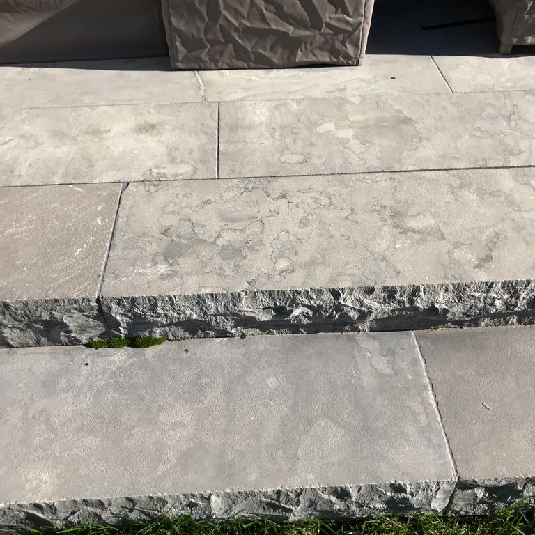 Application image for Highland Limestone. The image shows this material being used for landings and monolithic steps. The surface finish shown is flamed. The dominant color shown is gray. Regular and random color patterns.