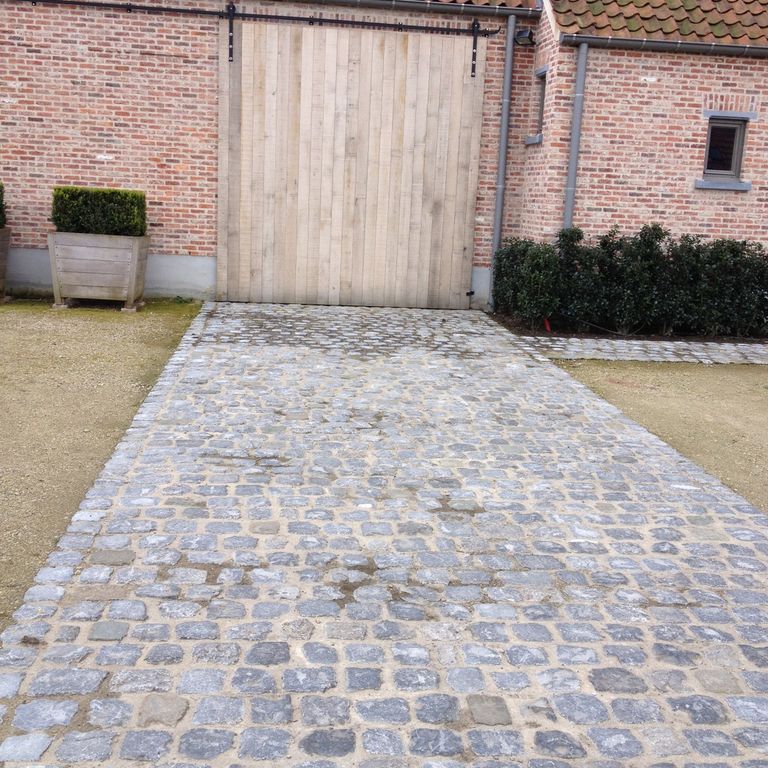 Application image for Reclaimed Belgian Bluestone Cobblestones. The image shows this material being used in a driveway pavers application. The surface finish shown is . The dominant color shown is gray. The color mix creates a warm feeling.