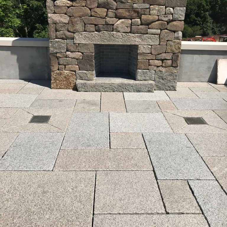 Feature image for Reclaimed Rockport Granite. The image shows this material being used in a patio pavers application. Dominant colors shown are beige and gray; with black, pink, white, tan and cream secondaries. The color mix creates a warm feeling. Speckled color pattern.
