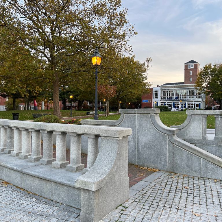 Feature image for Chelmsford Gray Granite. The image shows this material being used for architectural elements and patio pavers. The surface finish shown is honed. The dominant color shown is gray; with blue and white secondaries. The color mix creates a warm feeling. Fine speckled color pattern.