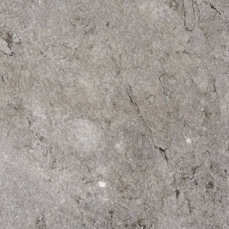 Close-up image for Dawn Haze Limestone. The surface finish shown is flamed. The dominant color shown is gray; with beige, brown, green, purple, white and tan secondaries. Exhibits 