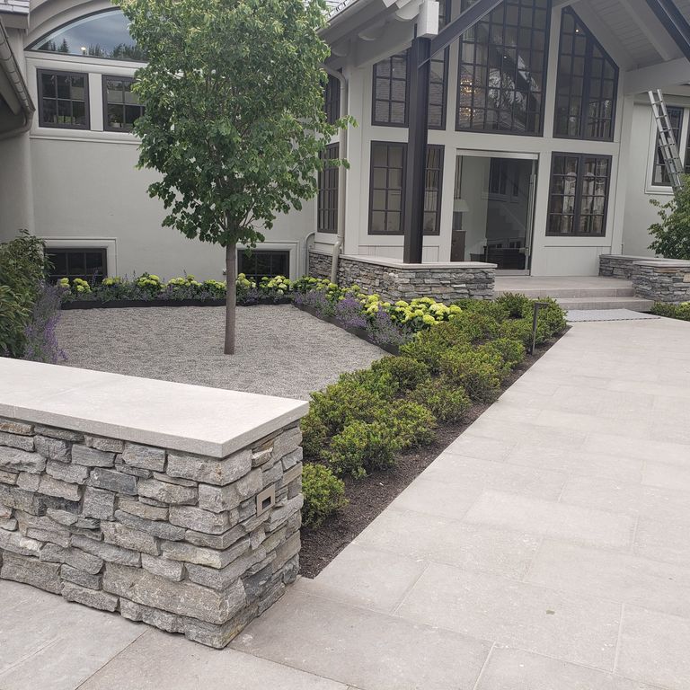 Application image for Limestone - Portuguese Dawn Haze. The image shows this material being used for wallstone cap, driveway pavers and patio pavers.