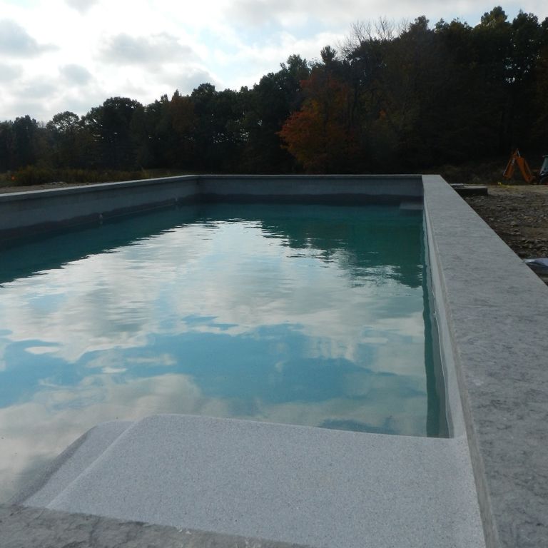 The image shows this material being used for pool coping, pool deck pavers and . The surface finish shown is flamed. The dominant color shown is gray; with a purple secondary. The color mix creates a cool feeling. Regular color pattern.