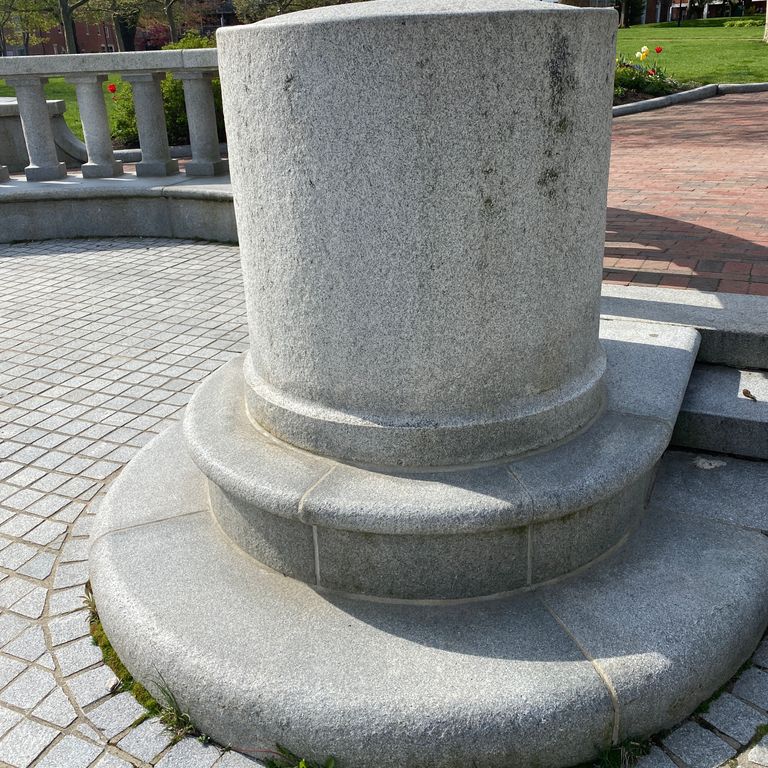 Application image for Kitledge Gray Granite. The image shows this material being used for architectural elements, patio pavers and posts. The surface finish shown is sand blasted. The dominant color shown is gray. The color mix creates a warm feeling. Fine speckled color pattern.
