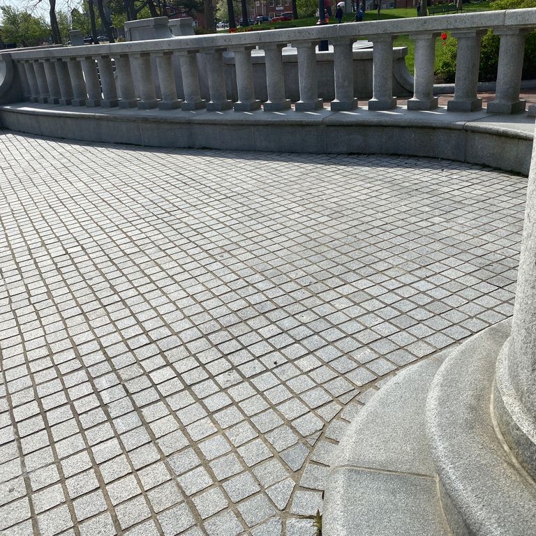 Application image for Kitledge Gray Granite. The image shows this material being used for architectural elements, landscape curbing & edging, patio pavers and monolithic steps. The dominant color shown is gray. The color mix creates a cool feeling. Speckled color pattern.