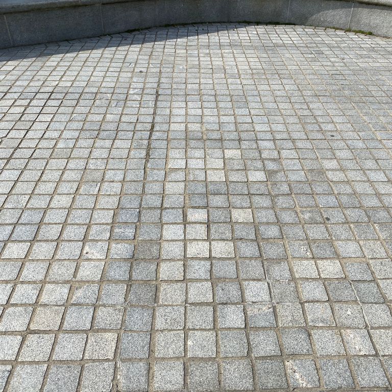Application image for Kitledge Gray Granite. The image shows this material being used for architectural elements and patio pavers. The dominant color shown is gray. The color mix creates a warm feeling. Speckled color pattern.