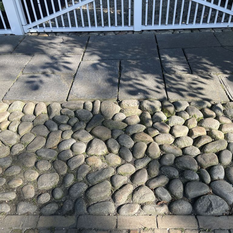 Application image for Beach Rounds. The image shows this material being used in a driveway aprons application. The surface finish shown is . The dominant color shown is gray. The color mix creates a warm feeling. Regular color pattern.