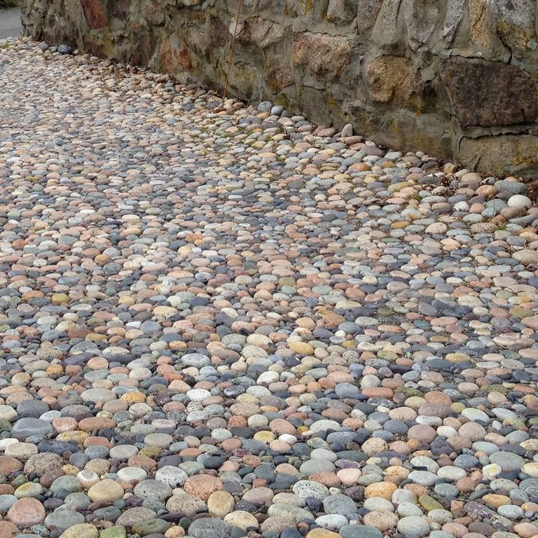 Application image for Beach Rounds. The image shows this material being used in a driveway pavers application. The surface finish shown is . Dominant colors shown are gray and tan. The color mix creates a warm feeling. Regular color pattern.