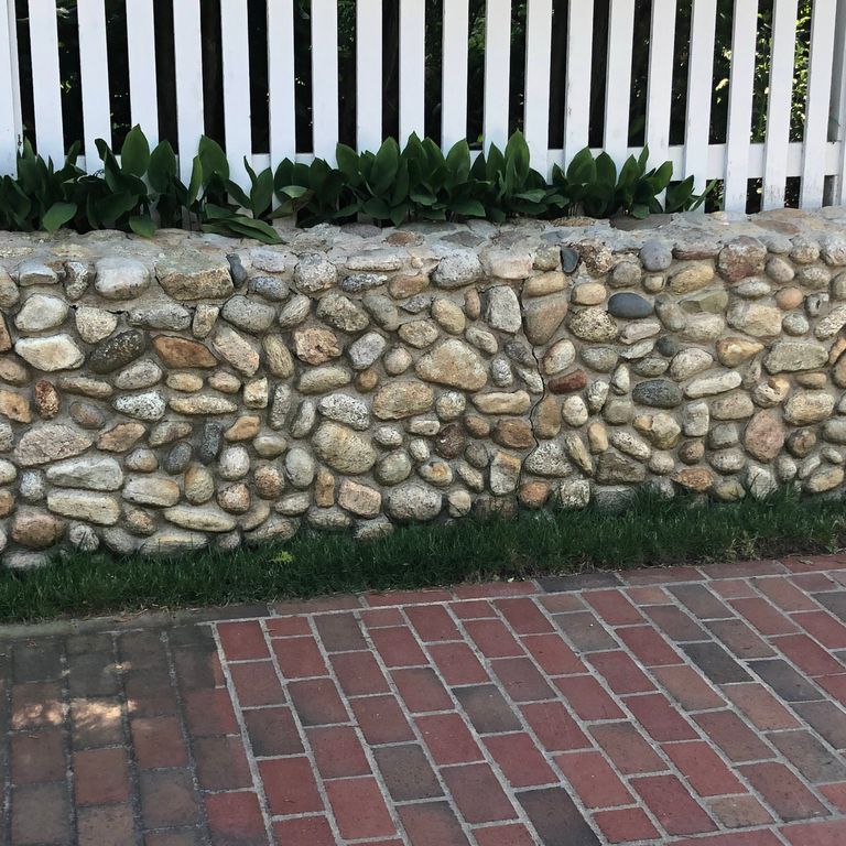 Application image for Beach Rounds. The image shows this material being used for landscape wallstone and full bed veneer. The surface finish shown is . The dominant color shown is gray. The color mix creates a warm feeling. Regular color pattern.