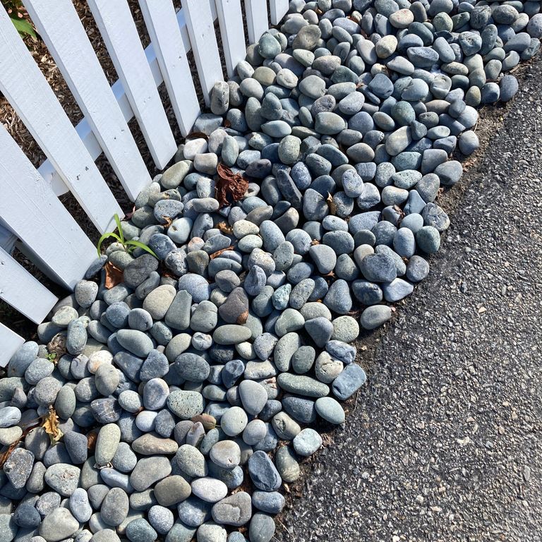 Application image for Beach Rounds. The image shows this material being used in a landscape curbing & edging application. The surface finish shown is a combination of natural and weathered. The dominant color shown is gray; with blue, green and white secondaries. The color mix creates a cool feeling.