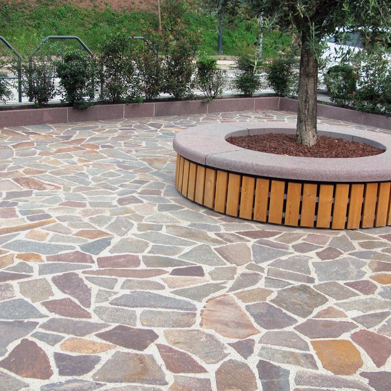 Feature image for Porphyry Natural Surface - Mixed Color. The image shows this material being used in a patio pavers application. Dominant colors shown are brown, green, gray, orange/rust, purple and red; with beige, blue, brown, green, orange/rust, purple, white, tan and cream secondaries. The color mix creates a warm feeling. Speckled and blotched color patterns.