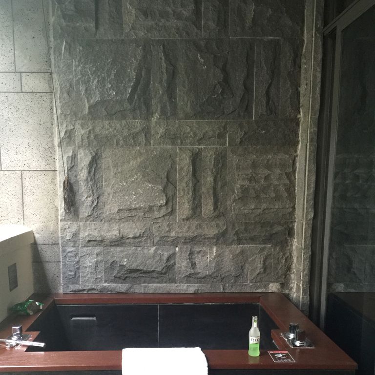 Feature image for Basalt - Ankar Black. The image shows this material being used for full bed veneer, thin veneer and interior cladding. The dominant color shown is gray; with brown and green secondaries. The color mix creates a cool feeling.