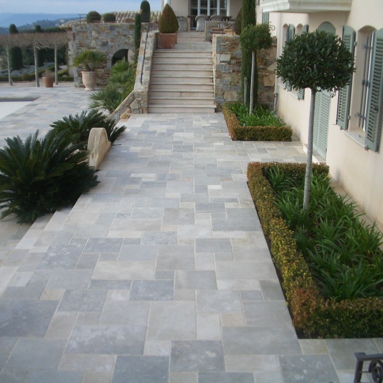 Feature image for Limestone - Mixed Blend. The image shows this material being used in a patio pavers application. The dominant color shown is gray; with beige, blue and white secondaries. The color mix creates a cool feeling. Blotched and cloudy color patterns.