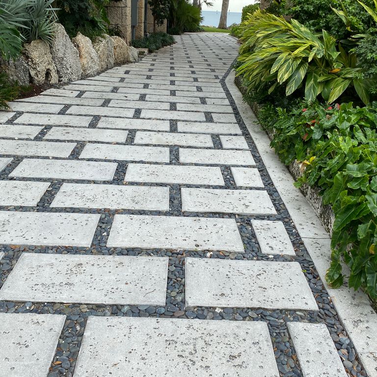 Feature image for White Coral Stone. The image shows this material being used in a path pavers application. Dominant colors shown are gray and white. The color mix creates a cool feeling. Regular and coarse speckled color patterns. Contains mineral inclusions.