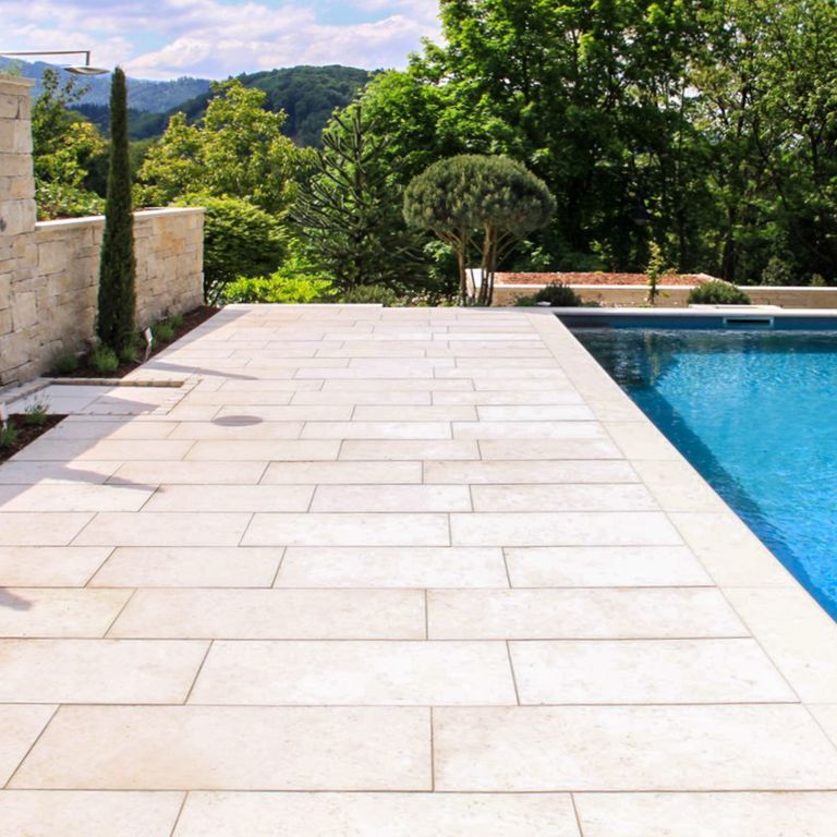 Application image for Bavarian Limestone - Beige. The image shows this material being used for pool coping and pool deck pavers. The dominant color shown is cream. The color mix creates a warm feeling. Regular and random color patterns.