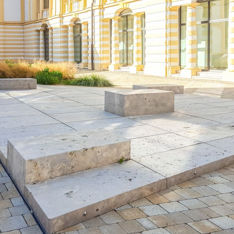 Application image for Bavarian Dolomite - Gray. The image shows this material being used for seating & benches and patio pavers. The surface finish shown is flamed. Dominant colors shown are gray and tan. The color mix creates a warm feeling. Random color pattern. Contains voids.