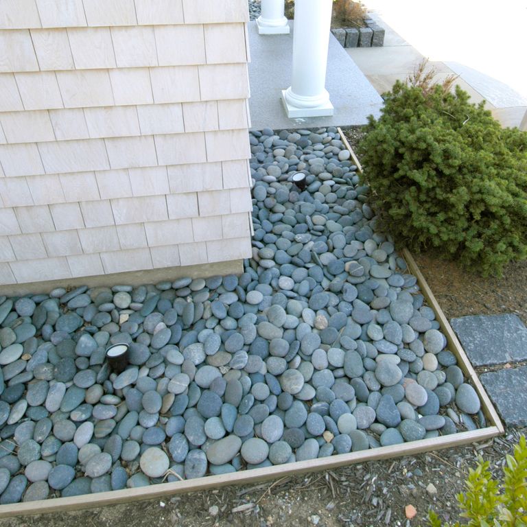 Feature image for Granite Beach Pebbles. The image shows this material being used in a garden accents application. Dominant colors shown are blue and gray; with green, white and tan secondaries. The color mix creates a cool feeling. Fine speckled color pattern.
