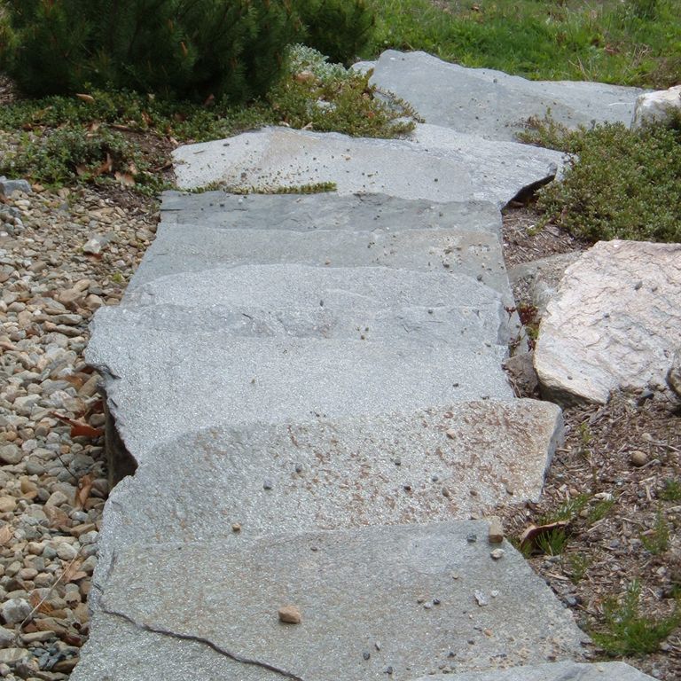 Application image for Chester Granite. The image shows this material being used in a monolithic steps application. The surface finish shown is natural cleft. Dominant colors shown are blue and gray; with a white secondary. Exhibits 