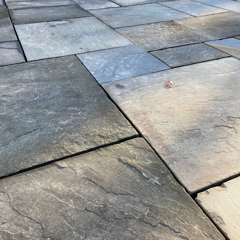 Feature image for Reclaimed Bluestone. The image shows this material being used in a patio pavers application. Dominant colors shown are brown and gray; with beige, blue, green, purple, white, tan and cream secondaries. Random color pattern.
