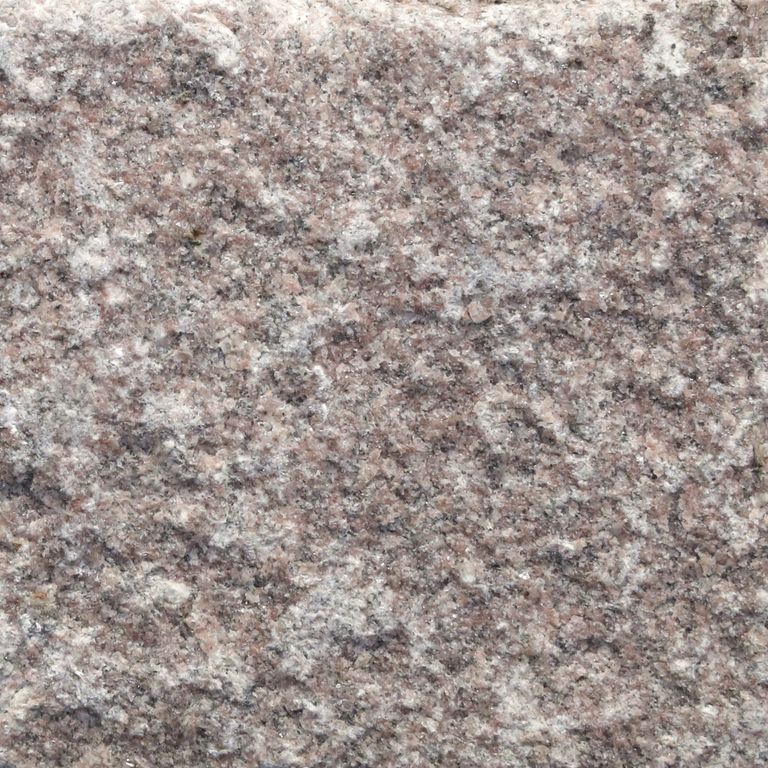 Close-up image for Granite Cobblestones - Dusty Rose. The surface finishes shown are split-face, split-face with flat plane and tumbled. Dominant colors shown are gray and purple; with beige, red and white secondaries. Exhibits 