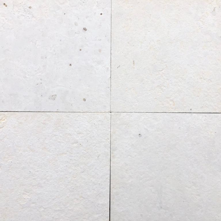Close-up image for Blanco Limestone. The surface finish shown is brushed. The dominant color shown is white; with gray and cream secondaries. The color mix creates a cool feeling. Solid and cloudy color patterns.