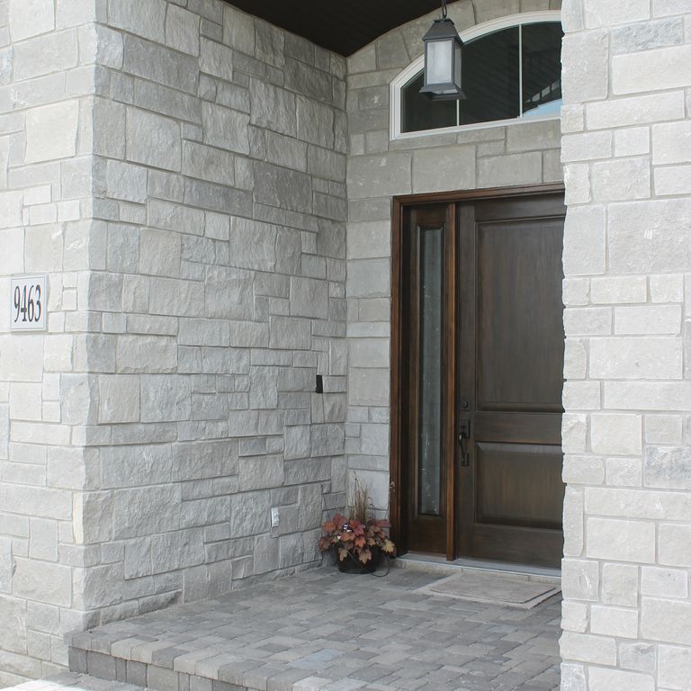 Feature image for Platinum Limestone. The image shows this material being used for full bed veneer and thin veneer. The dominant color shown is gray; with beige, white and cream secondaries. Solid, regular and cloudy color patterns.