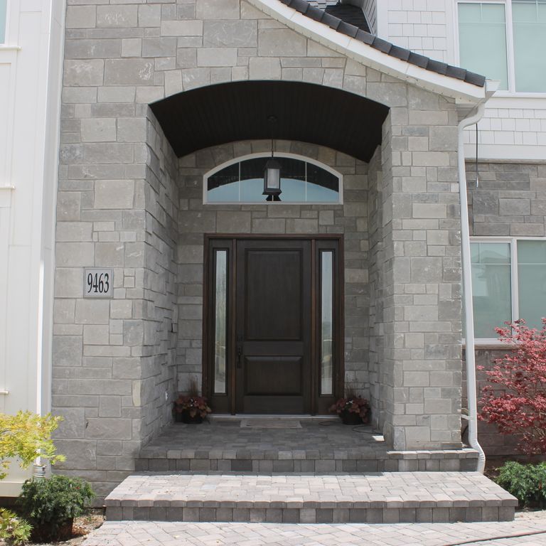 Application image for Platinum Limestone. The image shows this material being used for full bed veneer and thin veneer. The surface finish shown is split-face. The dominant color shown is gray; with a white secondary. The color mix creates a warm feeling. Regular color pattern.
