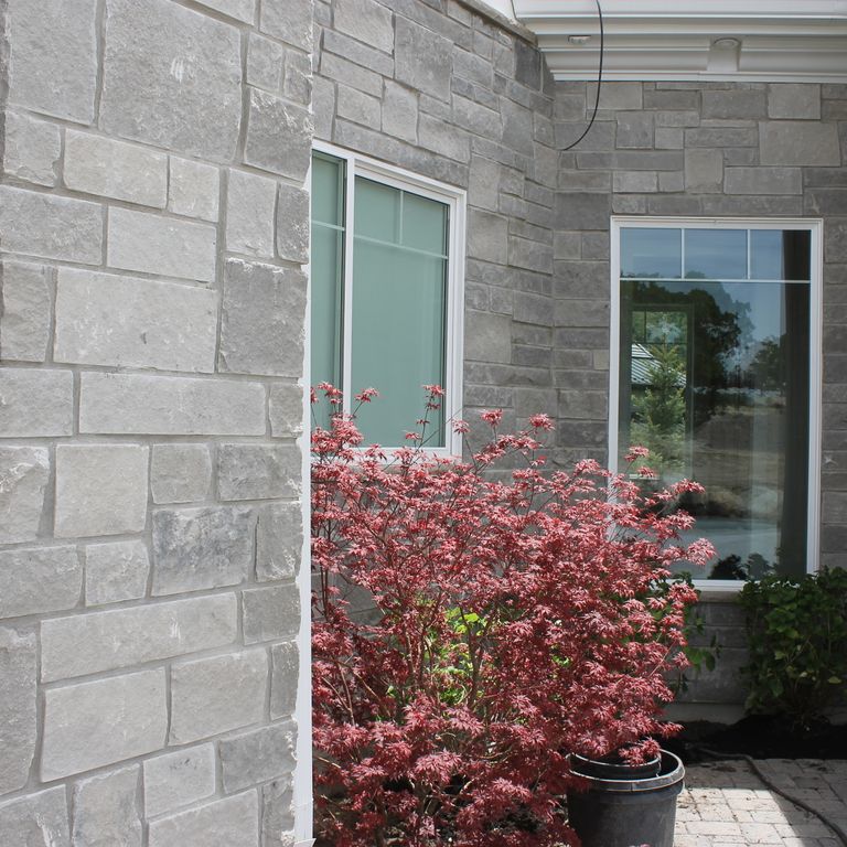 Application image for Platinum Limestone. The image shows this material being used for full bed veneer and thin veneer. The surface finish shown is split-face. The dominant color shown is gray; with a white secondary. Regular color pattern.